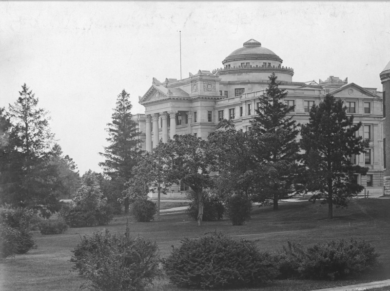 The front and the north sides of Beardshear Hall from central campus. Trees and shrubs in great abundance are in the middle and foreground of this image.