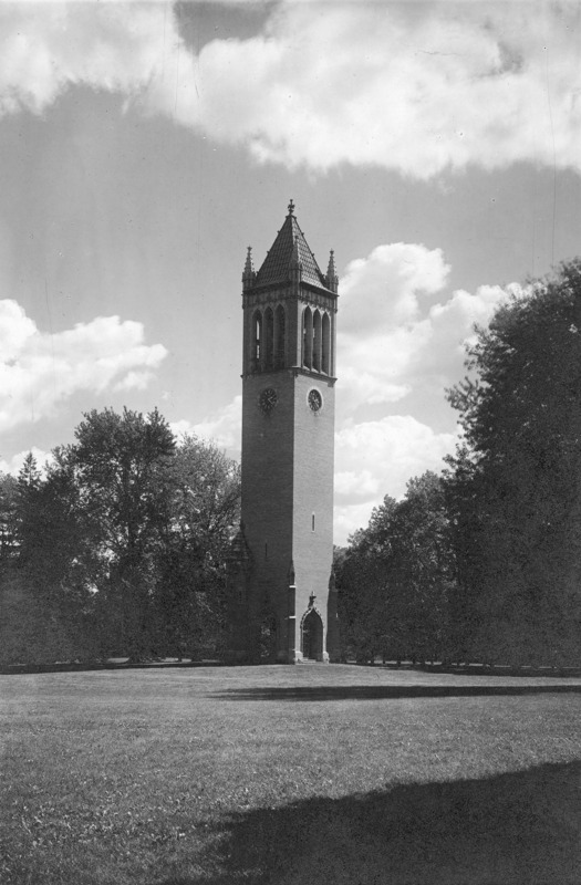 The north and west sides of the Campanile against a backdrop of trees and clouds at 2:22 pm. Two large dark tree shadows play across the foreground lawn; one of the trees is outside the image on the right, another tree is partially within the image on the right.