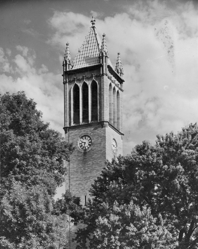 The Campanile in August 1945. This is a close up view of the top of the Campanile emerging from the center of a grove of trees that surround the structure. The clock shows 9:33.