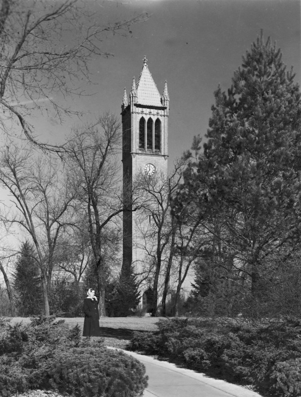 The Campanile as seen from the south. The trees have lost their leaves. A lone woman in coat and scarf stands on the sidewalk in the near distance. The clock shows 11:36.