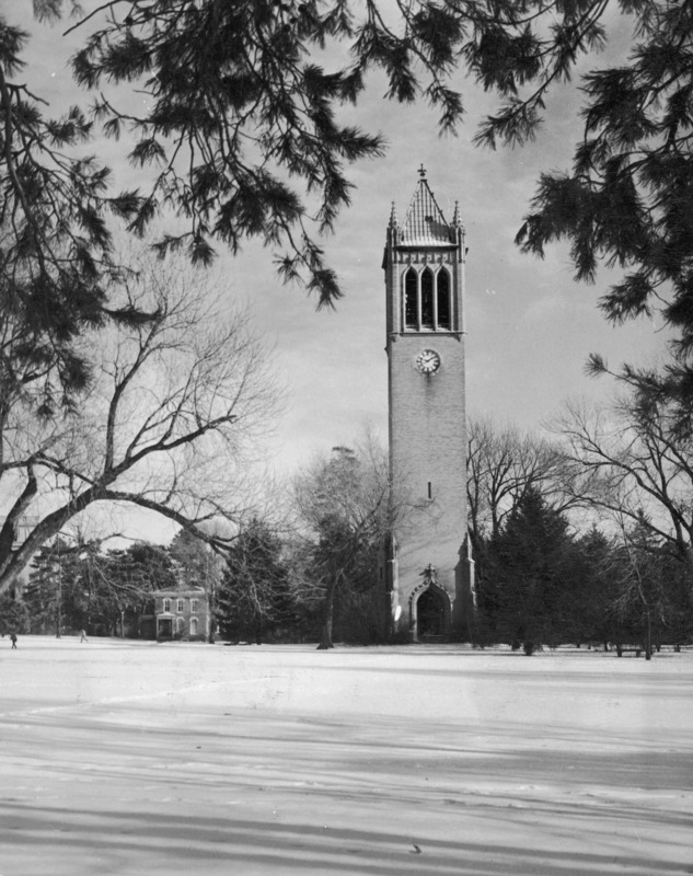 The Campanile in January 1949. Long shadows play on the snow between the camera and the tower. The clock shows 10:10. Sloss House can be seen to the left of the Campanile, both enshrouded by trees.