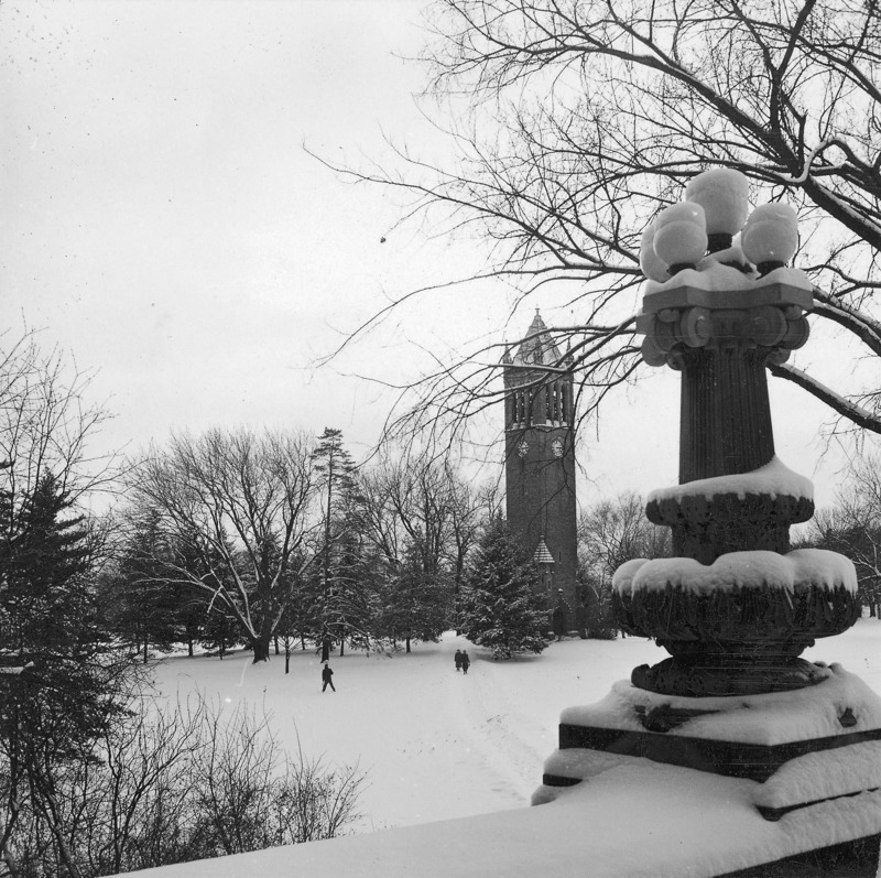 The Campanile in winter as seen from the portico of Curtiss Hall. Clock shows 3:15. A trail through the snow toward the Campanile can be seen with two people at the far end. One of a set of two photographs, the other being: 4-8-I.Campanile.230-7-3-2.