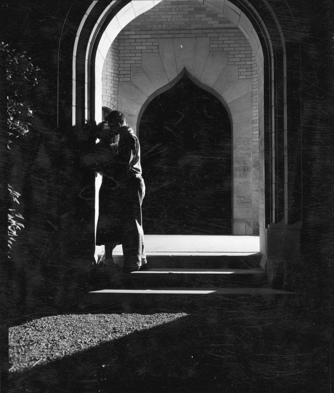 A backlighted couple kissing under the Campanile. The legend on the mount reads: "The tradition of becoming a coed.".