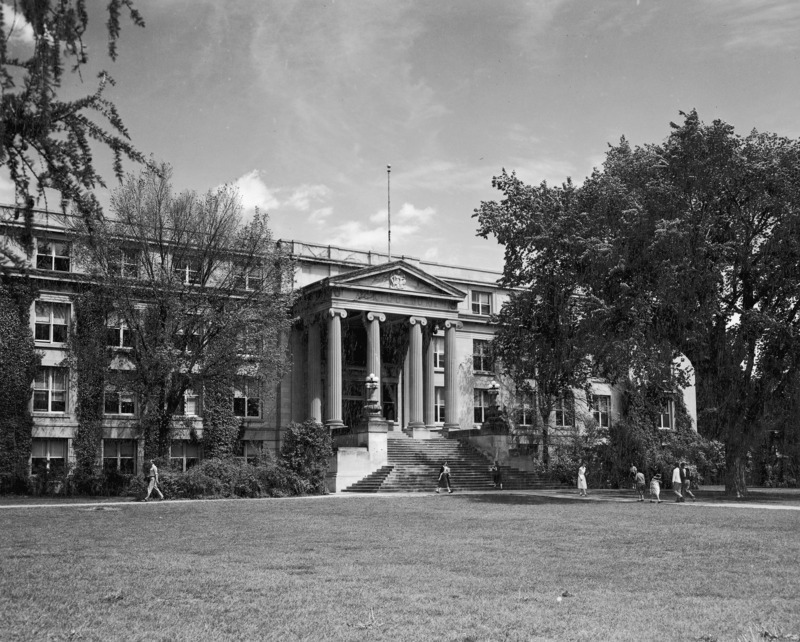 Students walk in front of Curtiss Hall as leaves begin to emerge from the surrounding trees.