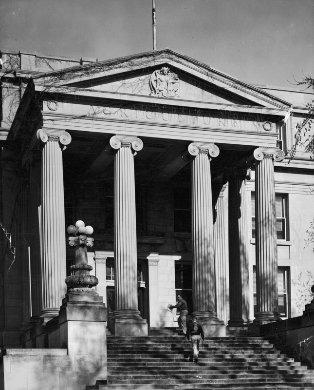 Two men climb the steps of Curtiss Hall towards the columns and pediment of the portico.