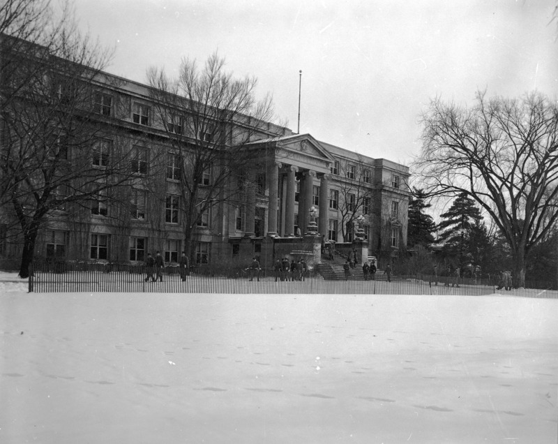 View of the front entryway of Curtiss Hall, with snow on the ground and a class of ROTC cadets leaving the building.