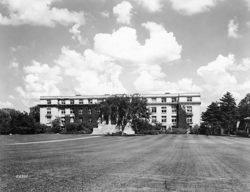 Agriculture Hall (Curtiss Hall) front (west) facade, is viewed from the southwest side of central campus, with ivy on the building and few trees other than the one in front of the steps, and Schloss House on the right.