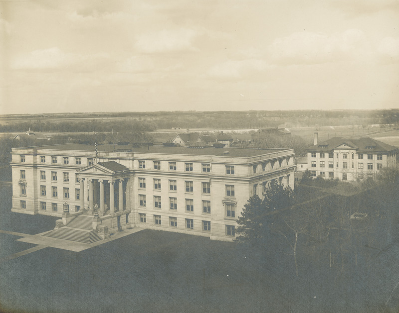 An aerial view of newly completed Agriculture Hall (Curtiss Hall), possibly from the Campanile, shows some of the buildings to its east. These include the Dairy Building (East Hall after 1928) and the roofs of the Horse Barn (Landscape Architecture after 1930), the twin Stock Judging Pavilions, and the Power and Heating Plant.