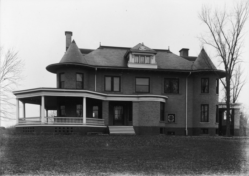 A full view of the north side of the Knoll occupies the center frame. The wrap around porch, front entry way and the tower are clearly visible.