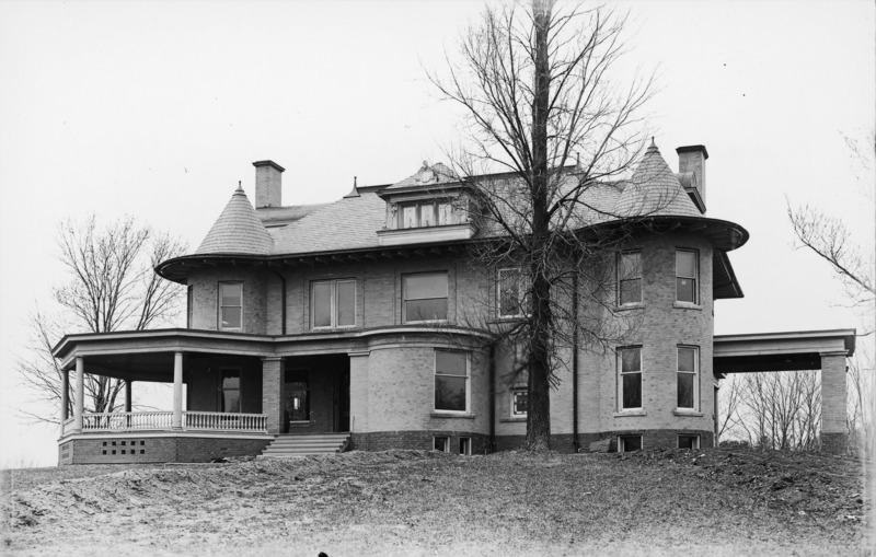 The Knoll is partially framed by leafless trees. The porte cochere, front entrance and part of the wrap-around porch are visible.