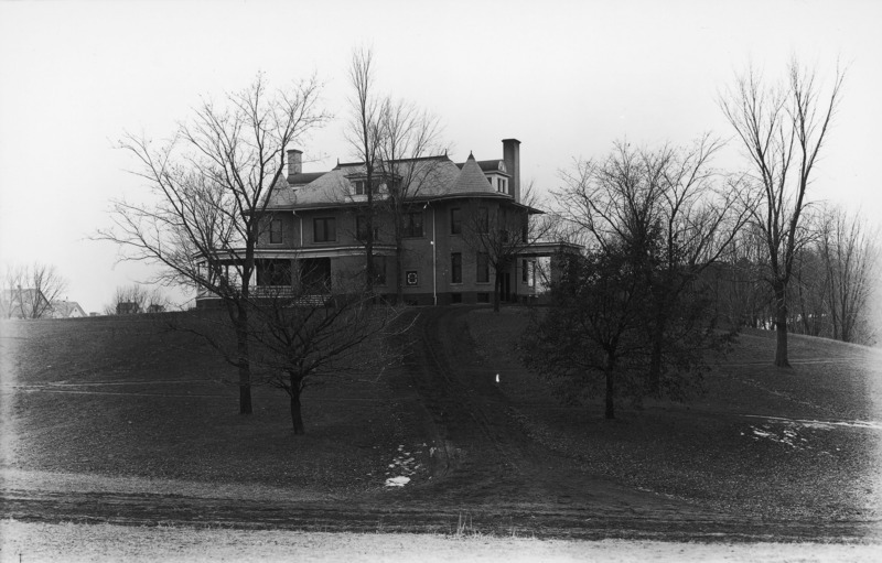 The eastern side of the Knoll is partially hidden by leafless trees. A dirt road runs from the foreground to the porte cochere. To the left, other buildings are in the distance.