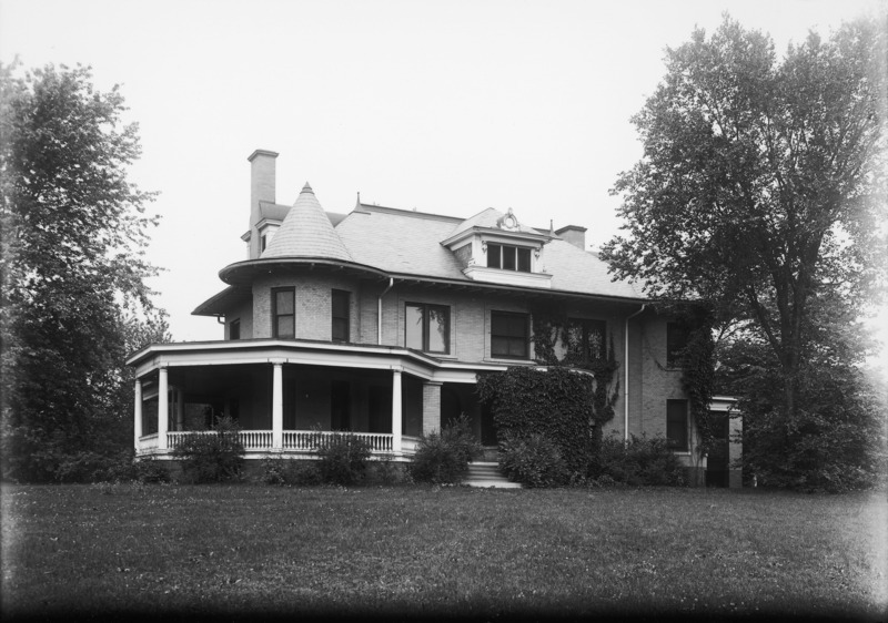 Thick ivy almost obscures the north front entryway of the Knoll. Trees flank the right and left sides of the building and bushes surround the wrap-around porch.