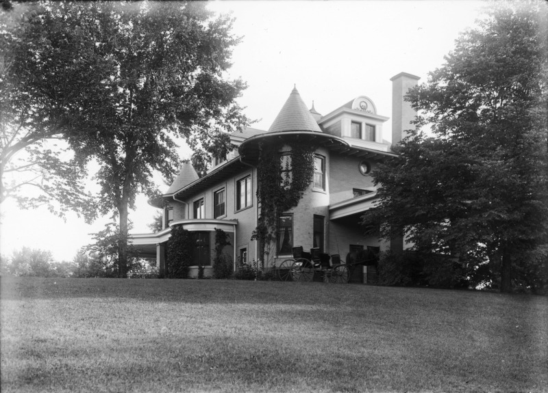 The northeast corner of the Knoll is in the center of this image. Ivy covers the tower and a horse and carriage is parked under the porte cochere.