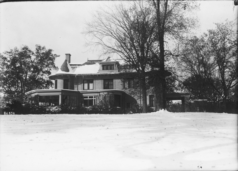 A snow covered lawn leads up to the east side of the Knoll. Trees and other shrubbery partially hide the north and south ends of the building. The Knoll roof is partially covered in snow.