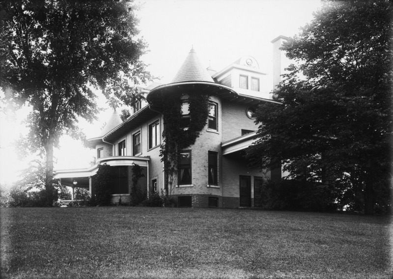 The northeast tower of the occupies the center of this ground level view of the Knoll. The second floor chimney and the porte cochere are partially hidden by trees and there is also a tree to the left of the frame.