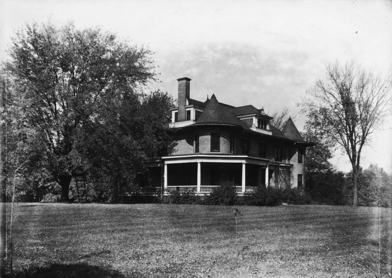 The wrap around porch, second floor dormer and southern chimney are all visible in this southeastern view of the Knoll. The house is surrounded by trees and the lawn.