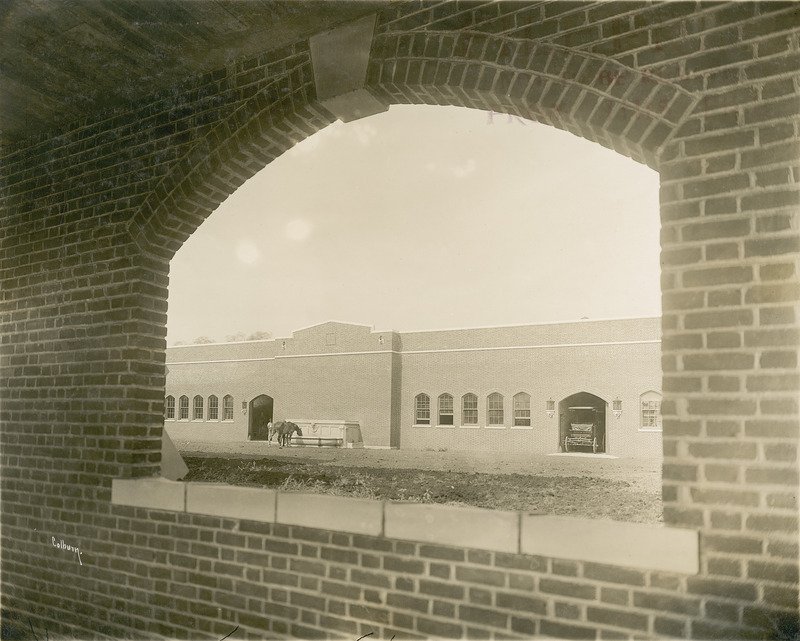 Lagomarcino Hall (then called the Quadrangle) in 1912. Man and horse can be seen in the distance toward the left. Photograph taken from inside the covered walkway.