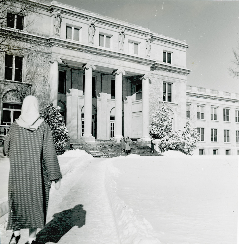 MacKay Hall in 1953. Surrounding area is covered in snow. Woman can be seen nearby on the left. Two other women are seen in the distance on the building steps.