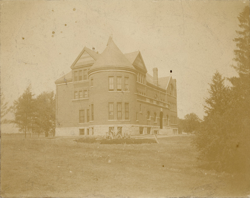 In this south view of Morrill Hall, the tower is at the center of the photograph. Flowers are growing in a bed across the road.