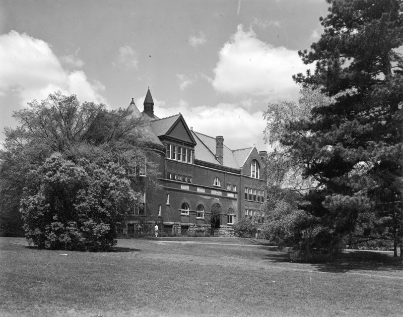 A woman is walking along the sidewalk in front of Morrill Hall.