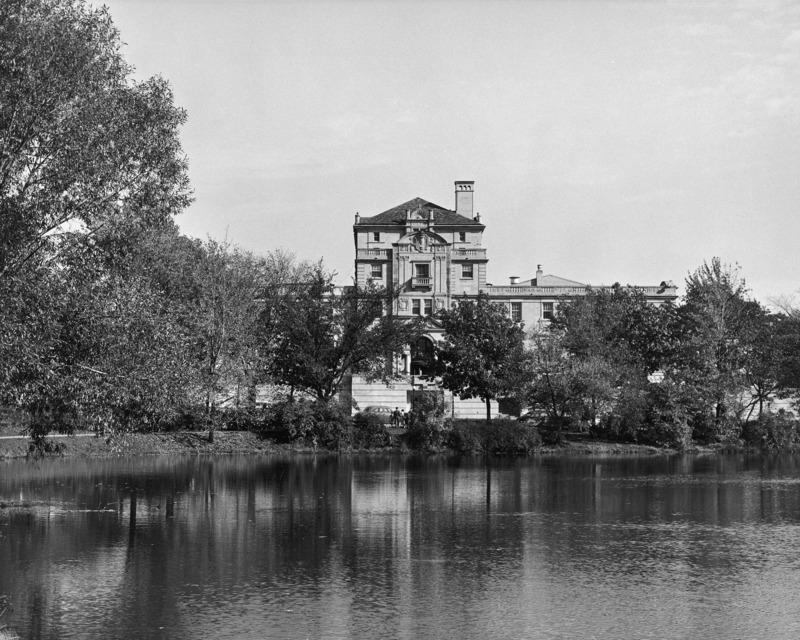 West side of the Memorial Union from across Lake LaVerne. The revolving door is visible in the terrace entrance, as is the street-level entrance near which there are cars and pedestrians.