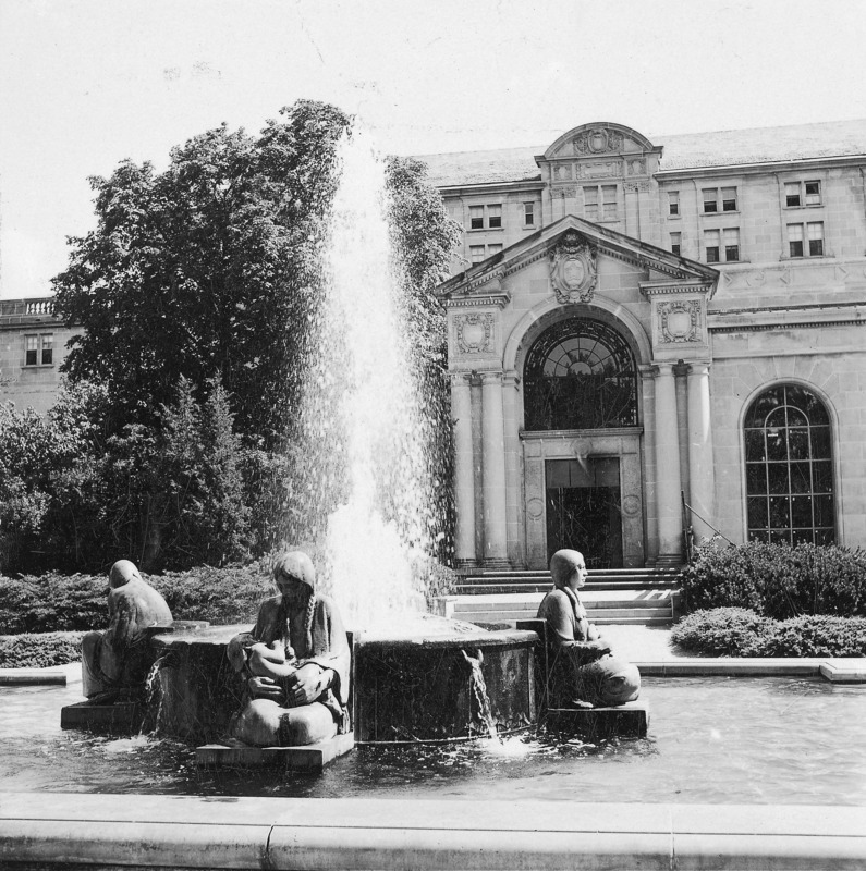 This 1952 photograph focuses on the Four Seasons Fountain in front (north) of the Memorial Union. The Four Seasons Fountain, which includes four Native American female figures, each representing one of the four seasons, is by Christian Petersen. The entrance to Gold Star Hall is in the background, and, to the right of that, one of the large arched windows of the completed northwest addition.