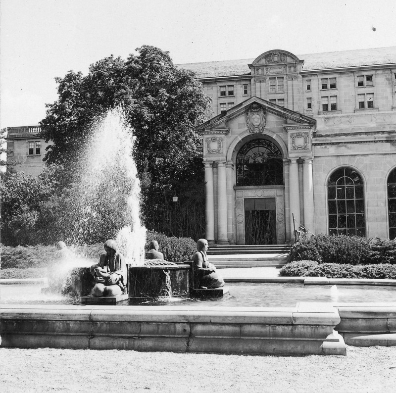 This 1952 photograph focuses on the Four Seasons Fountain in front (north) of the Memorial Union. The Four Seasons Fountain, which includes four Native American female figures, each representing one of the four seasons, is by Christian Petersen. The entrance to Gold Star Hall is in the background, and, to the right of that, one of the large arched windows of the completed northwest addition.