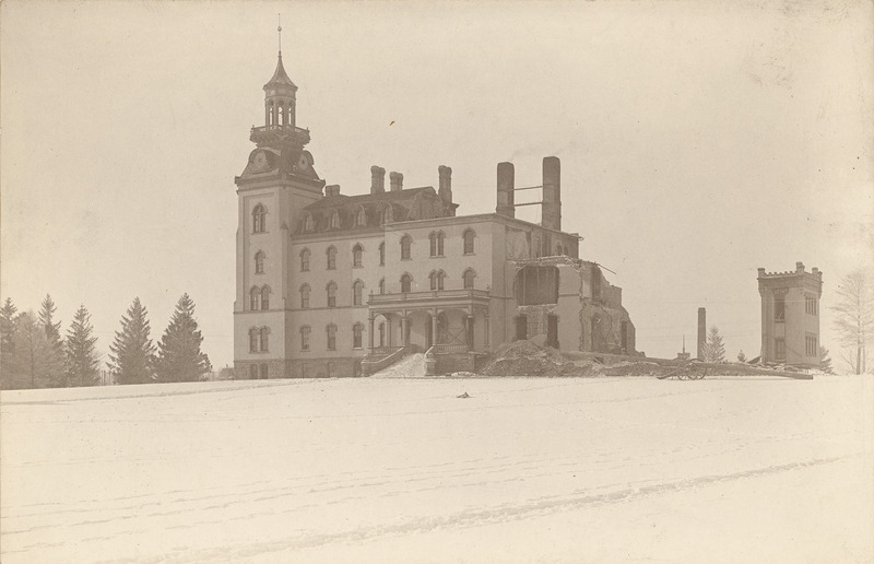 Old Main during deep winter following the December 1900 fire. The North wing has largely disappeared. The South Wing of the building is still in use. The ground is covered in snow.