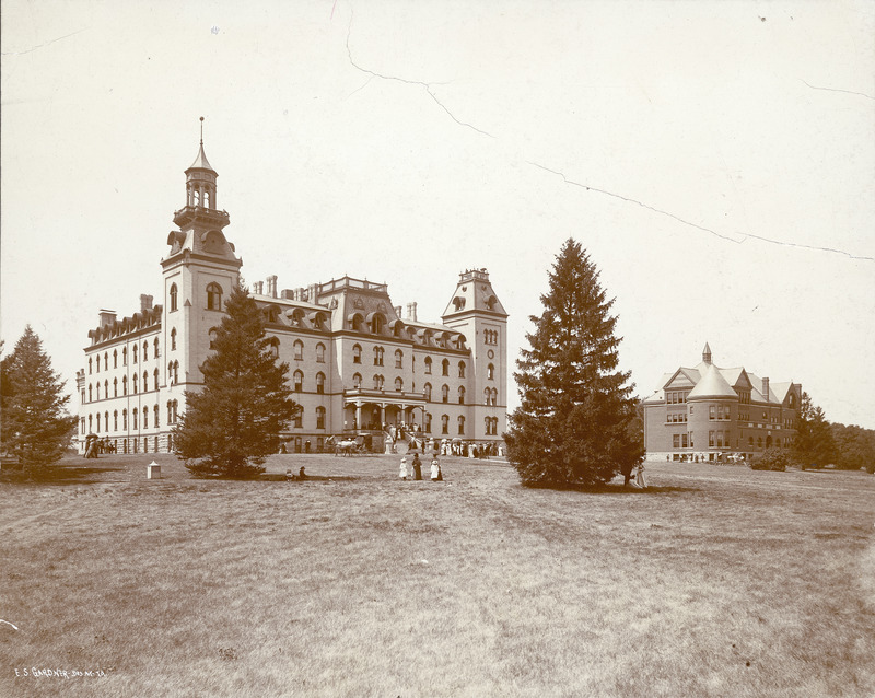 Old Main and Morrill Hall (constructed 1890-1891). A number of people are in front of each building as well as walking to the buildings.