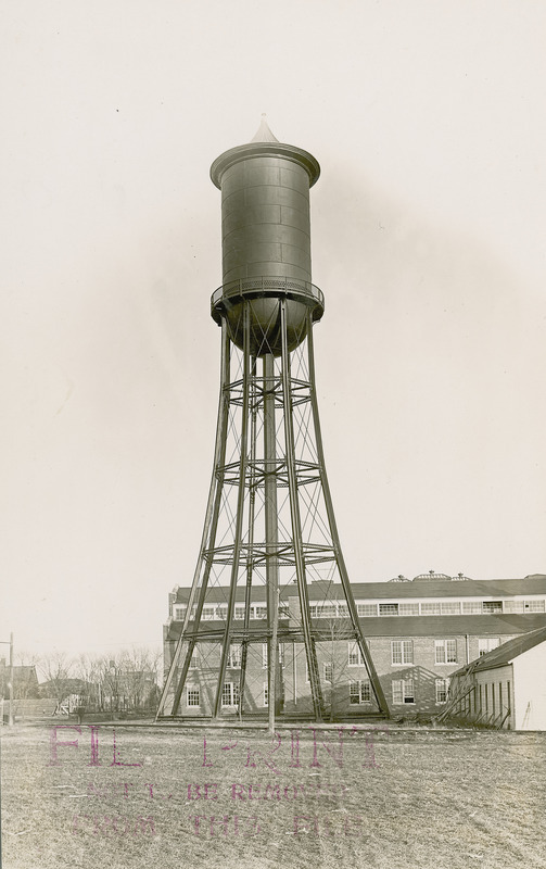 A full-length view of the Marston Water Tower with the Engineering Annex in the background and lawn in the foreground.