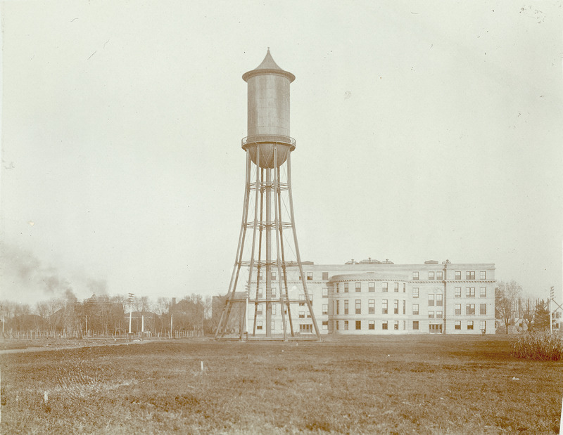 The Marston Water Tower is shown with Marston Hall in the background. There are also various other smaller buildings in the distance.