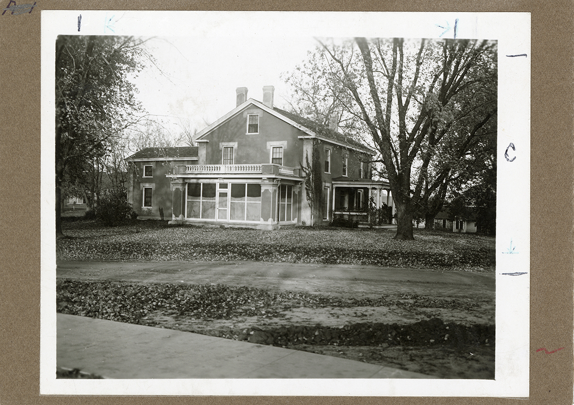 Photograph showing the south-west corner of the Farm House including both the west and south porches. The Creamery, First can be seen in the background to the right (west) of the Farm House. Annotation: “The Farm House, picture appears in 1915 Alumnus.”
