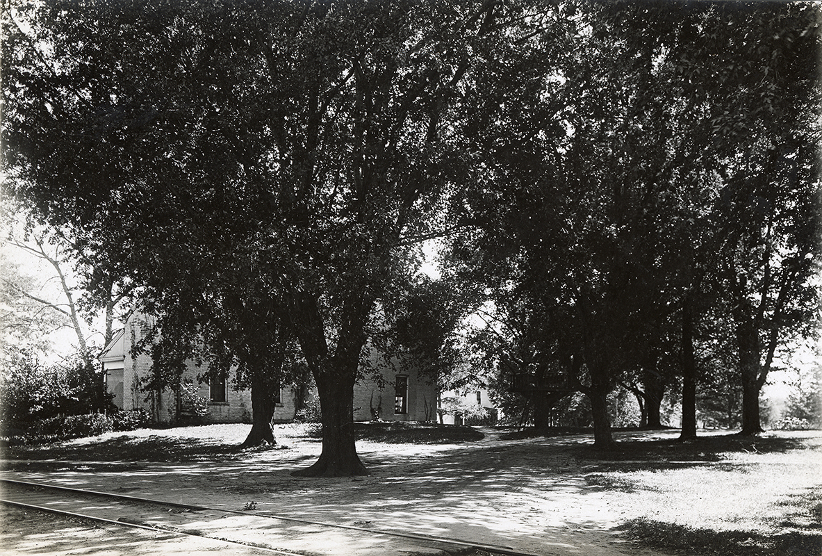 Photograph of Dinkey tracks as they run behind (north of) the Farm House. Annotation: “Farm House 1906. Motor track in foreground.”