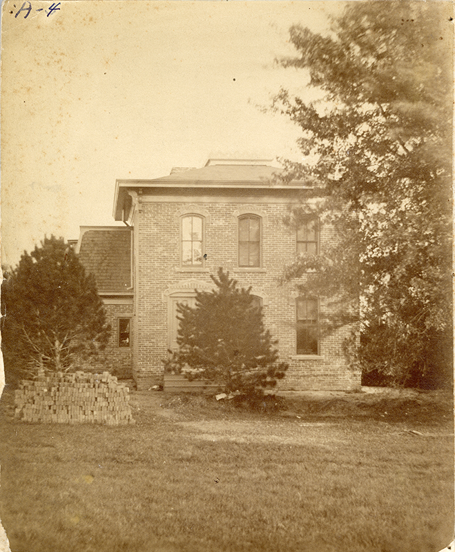 Photograph of Sloss House with a pile of bricks in the foreground.