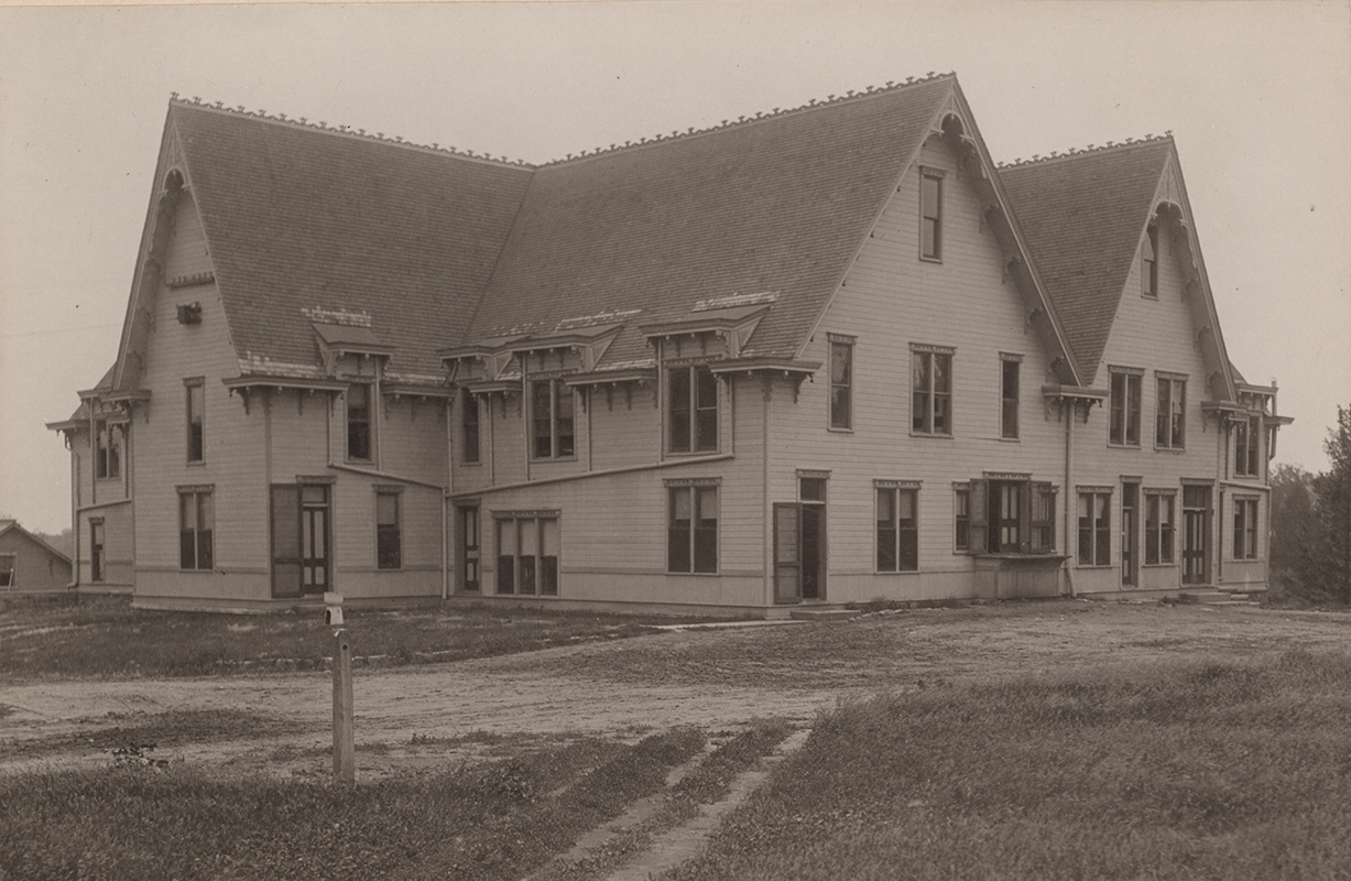 Photograph of the second creamery building. The photograph shows two sides of the building, which is two stories high with a steep roof.