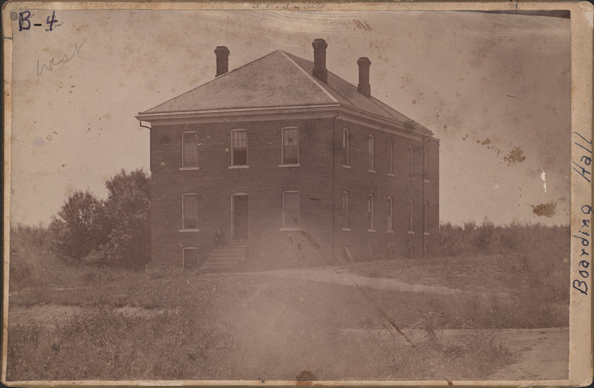 Photograph of two sides of West Boarding Cottage. It is a two story brick building, with three chimneys visible.