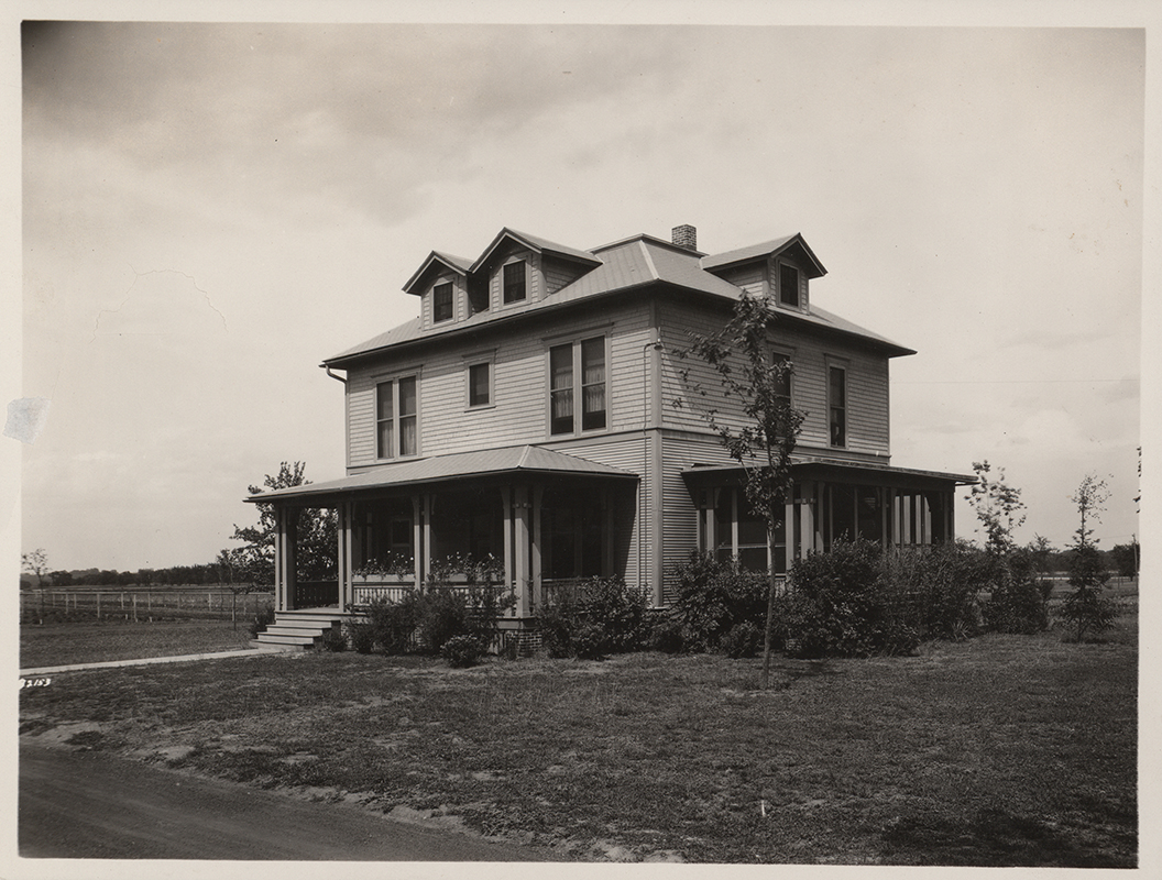 Photograph of Bevier House featuring the front and side. There is a covered front porch, and an enclosed porch on the side.