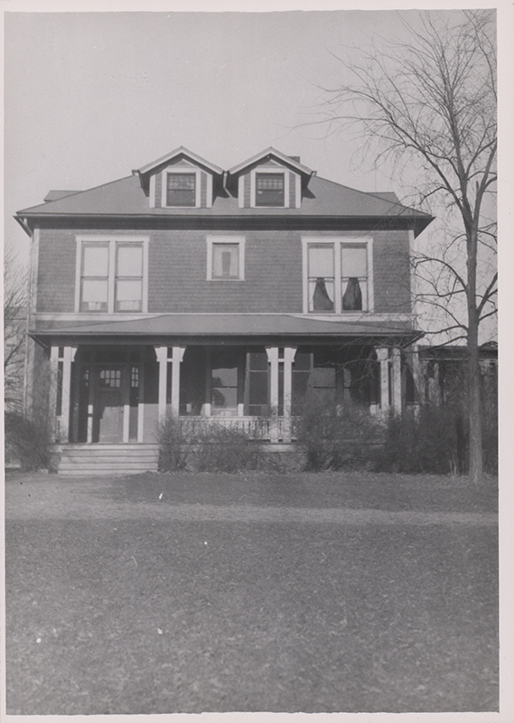Photograph of Bevier House from the front. It has a front porch with bushes in front. The trees and bushes do not have leaves. The caption reads "Sloss Family lived here from 1910-1925."