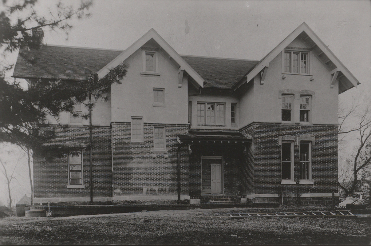 Photograph of International House. Several windows are broken and there is a ladder in the front yard.