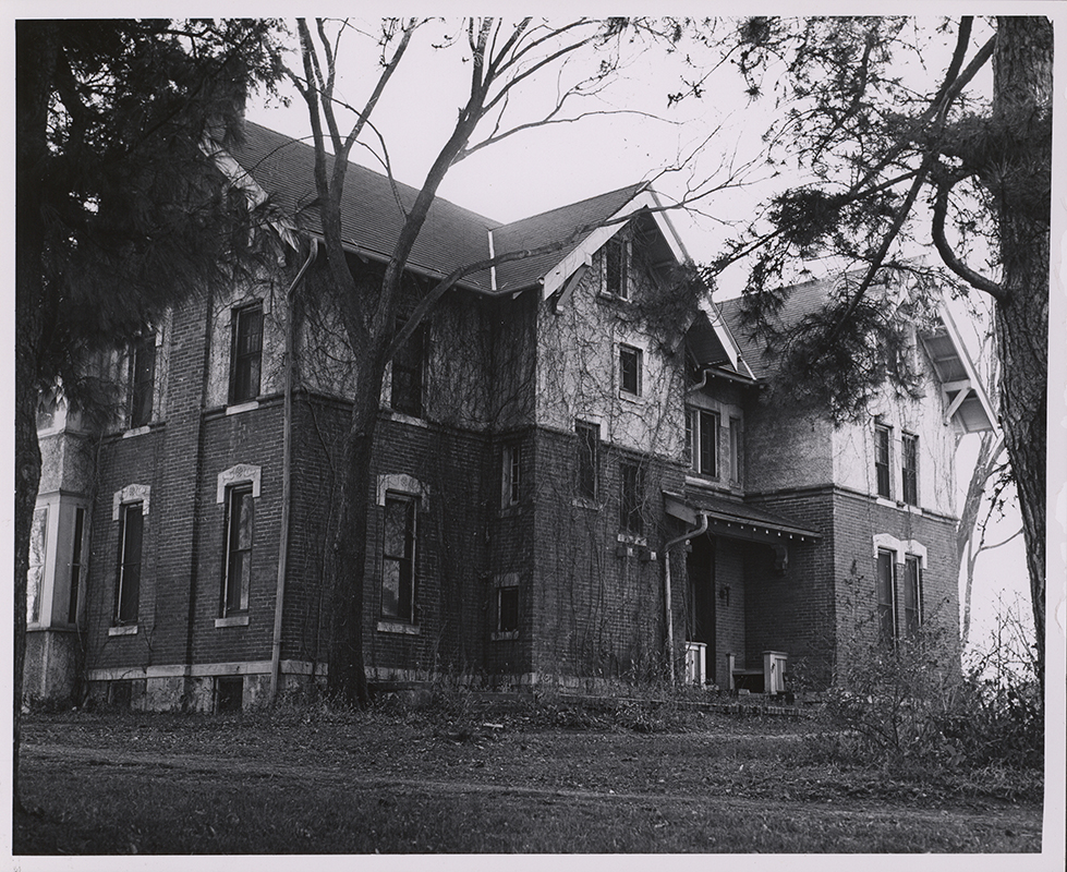 Photograph of International House showing one side and the front of the house. Ivy vines cover the front, and leafless trees are in the foreground.