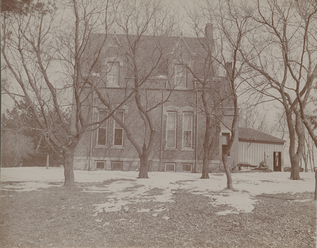 Photograph of the side of International House. The photo depicts a tall brick building with a one-story addition on the rights. Snow and leafless trees are in the foreground.