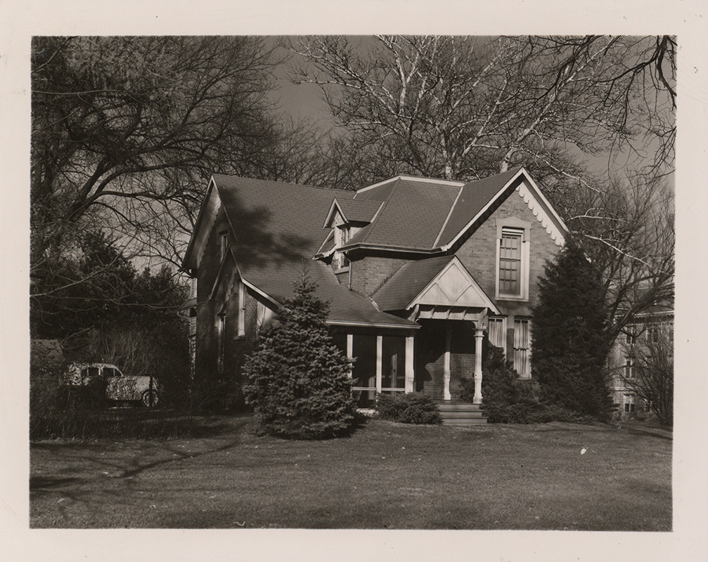 Photograph of the southwest corner of Osborn Cottage with a car parked facing the west side of the building.