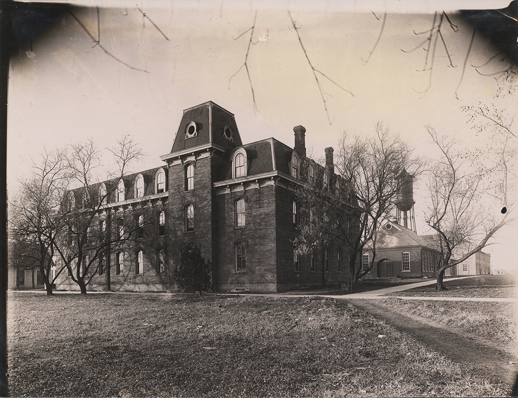 Photograph looking north-west at the southeast corner of the Laboratory of Mechanics. The Quarantine Hospital can be seen to the west (left) of the Laboratory and the Steam & Gas Lab, Marston Water Tower, and Building A can be seen to the north (right).