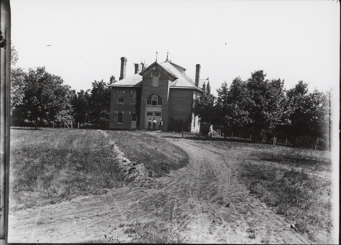 Photograph showing three people standing outside the north side of the Veterinary Hospital. Annotation: ''Veterinary Hospital view from north early 1900s?''