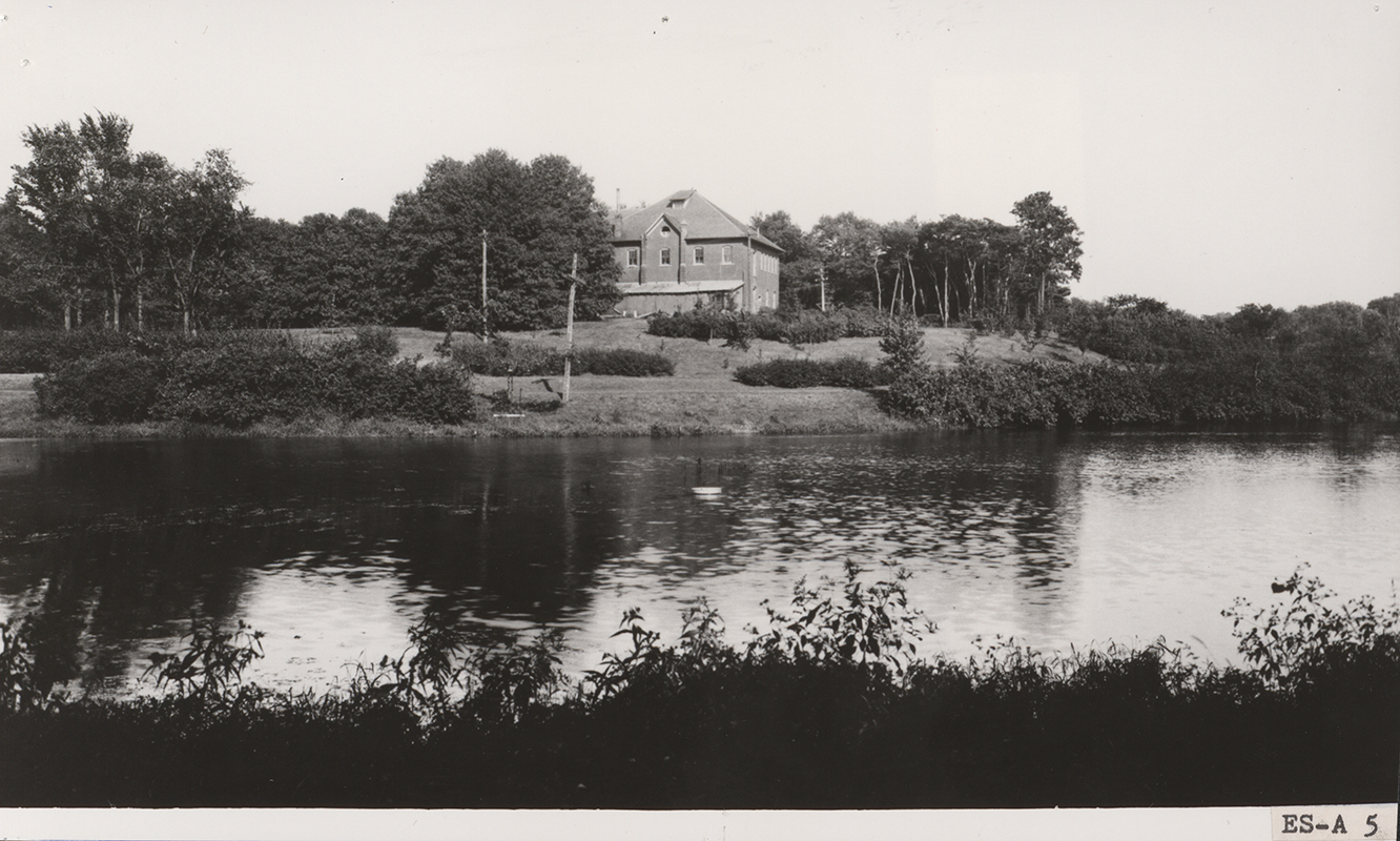 Photograph looking across Lake LaVerne at the west and south sides of the Veterinary Hospital. Annotation: "Old Carpenter & Paint Shop on site of M.U. Formerly the Veterinarians' Hospital, this structure was torn down in 1927."