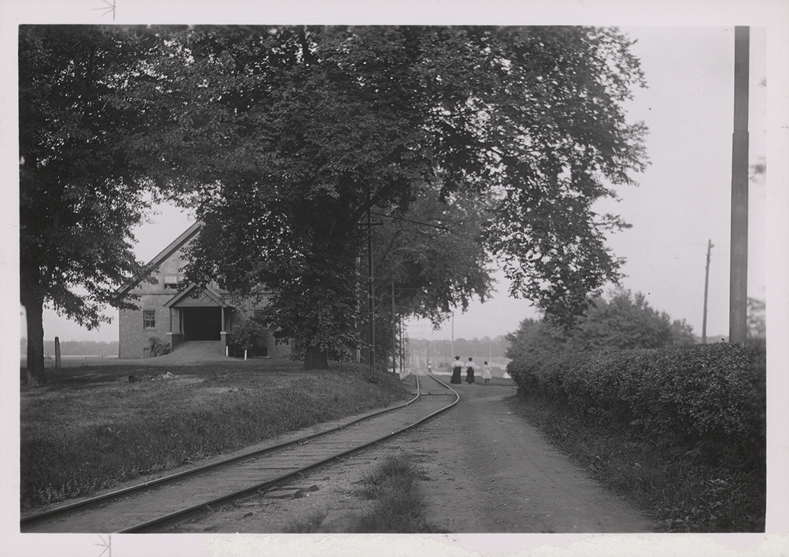 Photograph showing three people walking east along the Dinky tracks as they pass by Landscape Architecture when it was the Horse Barn.