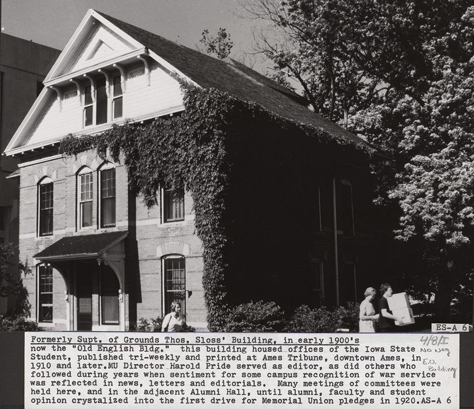 Photograph of three people walking past the northeast corner of the English Office Building. Part of Carver Hall can be seen to the south (left). Annotation: ''Formerly Supt. of Grounds Thos. Sloss' Building in early 1900's now the "Old English Bldg" this building housed offices of the Iowa State Student, published tri-weekly and printed at Ames Tribune, downtown Ames, in 1910 and later. MU Director Harold Pride served as editor, as did others who followed during years when sentiment for some recognition of war service was reflected in news, letters and editorials. Many meetings of committees were held here, and in the adjacent Alumni Hall, until alumni, faculty and student opinion crystalized into the first drive for Memorial Union pledges in 1920.''