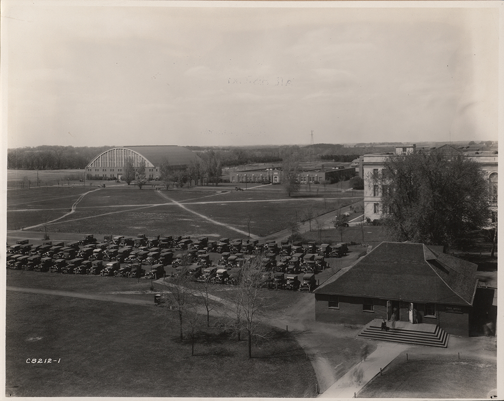 Photograph of cars parked west of the Hub when it was the Post Office. The Armory, Davidson Hall, and library can be seen in the north-west (background).