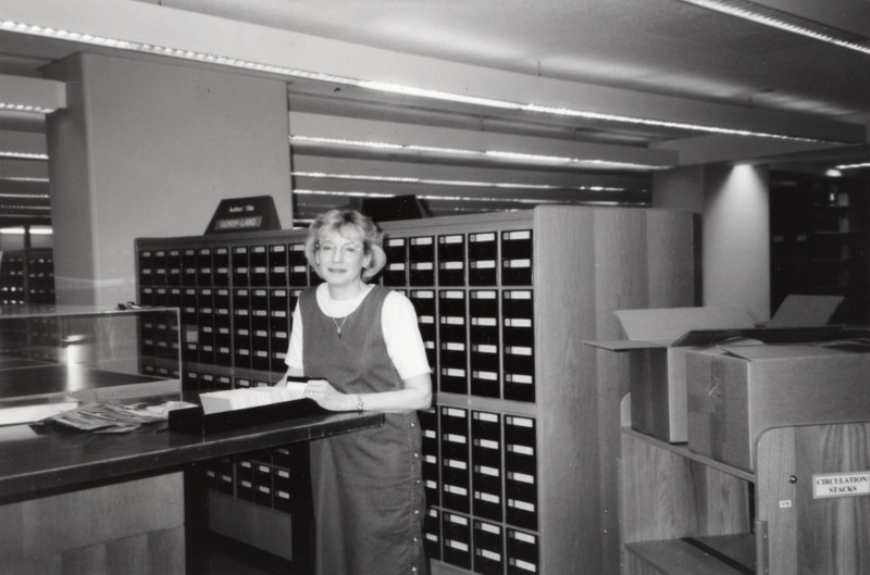 Olivia Madison, Dean of the Library, is looking through the card catalog located on the second floor.