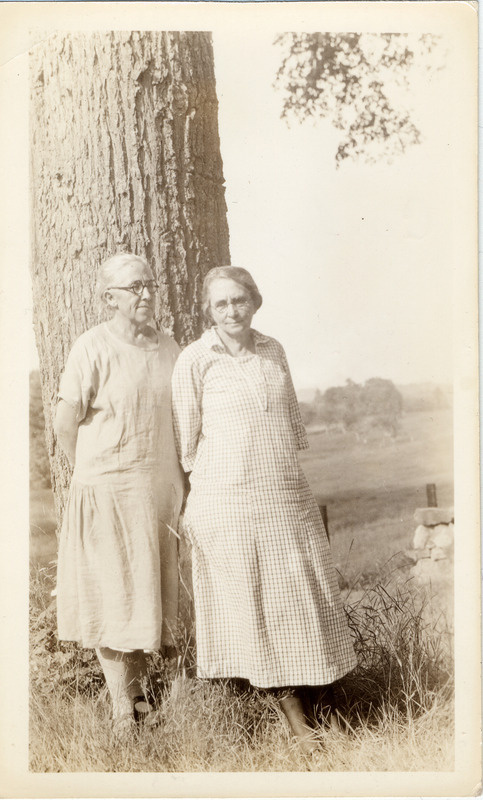 Carl and Mary, library staff, are standing under a tree in this rural setting.